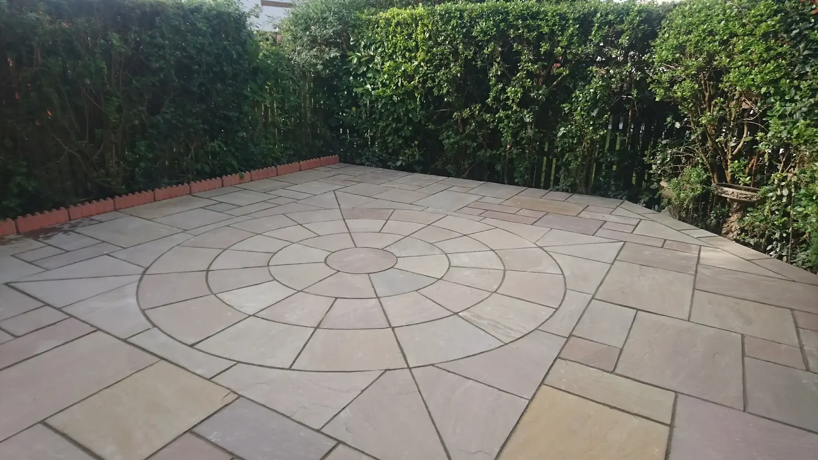 Circular paved patio set within a landscaped garden